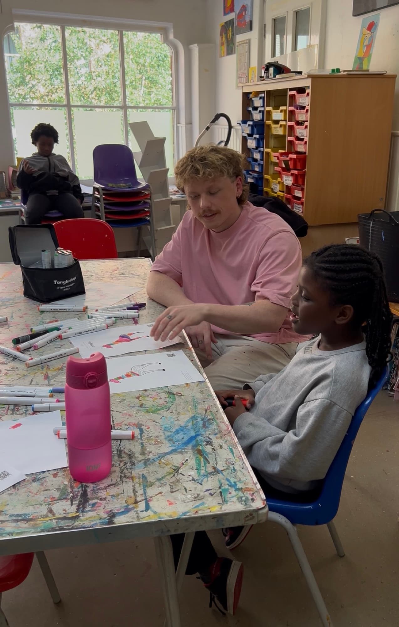 Doddz helping a child with her drawing